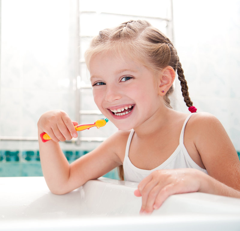 Little girl brushing teeth in bath